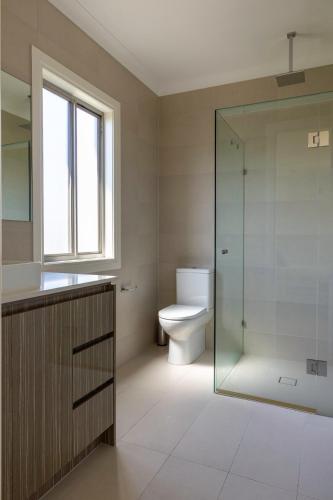a bathroom with a toilet and a glass shower at Spacious Home with Ensuites in Mount Waverley