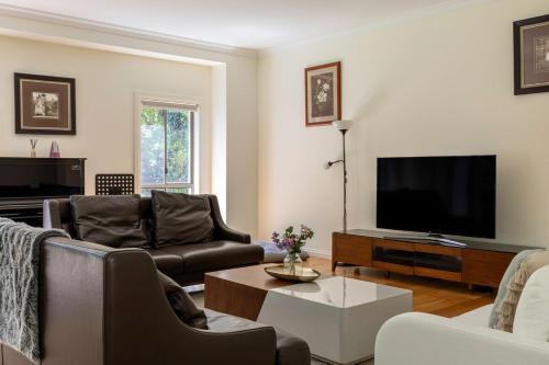 a living room with a couch and a tv at Spacious Home with Ensuites in Mount Waverley