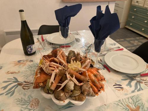 - une table avec une assiette de fruits de mer et une bouteille de vin dans l'établissement Chez Tipoulot - maison de pêcheur à 2 pas du port, à Fécamp