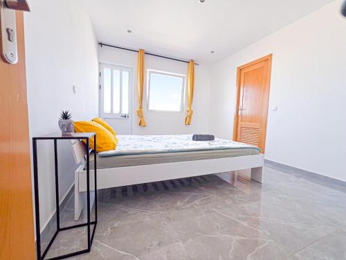 una cama en una habitación con dos ventanas en Brand new apartment in Mindelo, en Mindelo