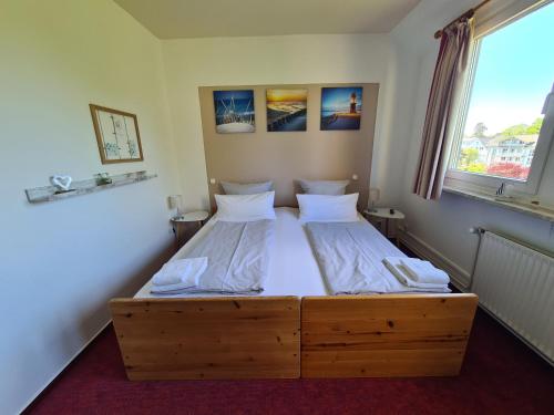 a bedroom with a wooden bed and a window at Zeitlos Hotel Garni in Scharbeutz
