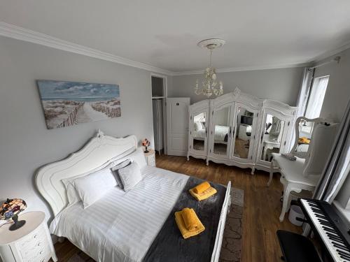 a bedroom with a white bed and a piano at Sami in Southend-on-Sea
