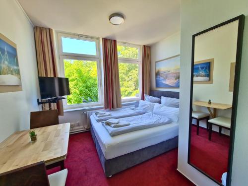 a hotel room with a bed and a desk and a mirror at Zeitlos Hotel Garni in Scharbeutz