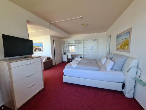 a living room with a white couch and a flat screen tv at Zeitlos Hotel Garni in Scharbeutz