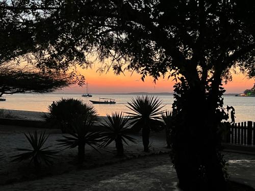 a sunset over the ocean with a boat in the water at Mangrove House in Lamu