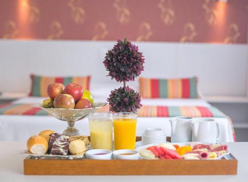 a tray of food with a plate of fruit and juice at Hotel Girassol Plaza in Palmas
