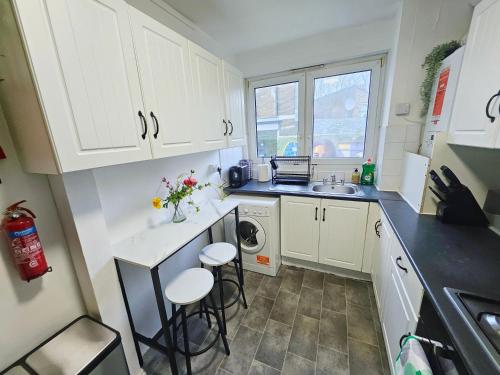 a small kitchen with white cabinets and a sink at Wellington Apartment in London