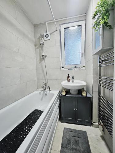 a bathroom with a white tub and a sink at Wellington Apartment in London