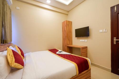 a hotel room with a bed and a flat screen tv at Yaad Inn in Cochin