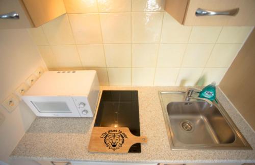 une petite cuisine avec un évier et un micro-ondes dans l'établissement l'Or dans la Mer, à Nice