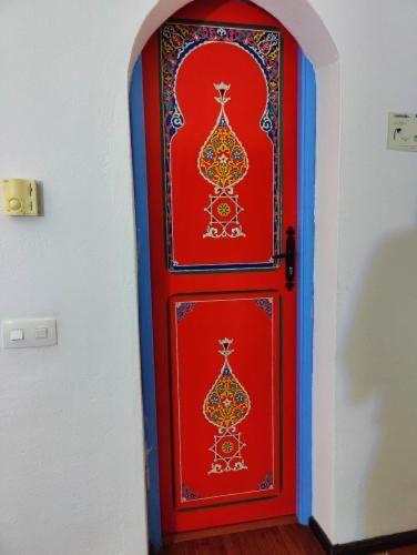 a red door with paintings on it in a room at Hotel Alkhalifa in Chefchaouene