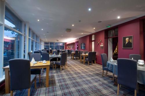 ein Restaurant mit Tischen, Stühlen und lila Wänden in der Unterkunft The Royal George Hotel in Perth