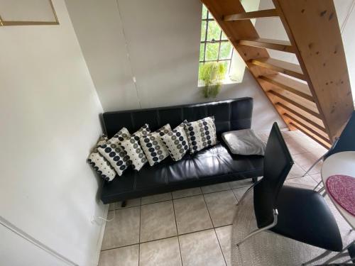 a black leather couch with pillows in a living room at Stutteri Skandihest Apartments in Billund