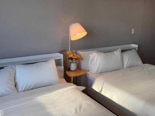 two beds in a room with a lamp and flowers at Serein_HongDae in Seoul