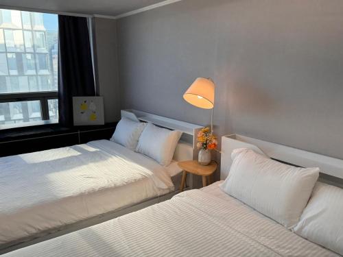 a bedroom with two beds and a lamp and a window at Serein_HongDae in Seoul