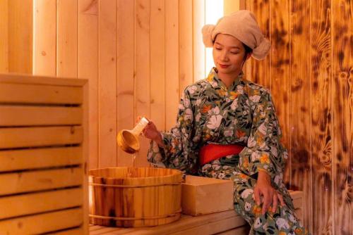 a woman is standing next to a wooden bucket at Lynn Times Thanh Thuỷ hotspring-KS 35 tầng- My Home in Phú Thọ