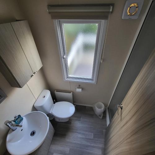 a small bathroom with a toilet and a window at Jasmine Corner - entertainment passes included - message for longer stays in Ringwood