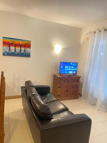Una sala de estar con un sofá de cuero y un televisor. en Suíte Deluxe Soares, en Prainha
