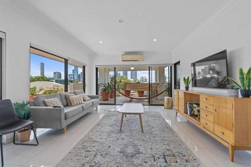 a living room with a couch and a tv at Lux Penthouse, Private Rooftop in Brisbane