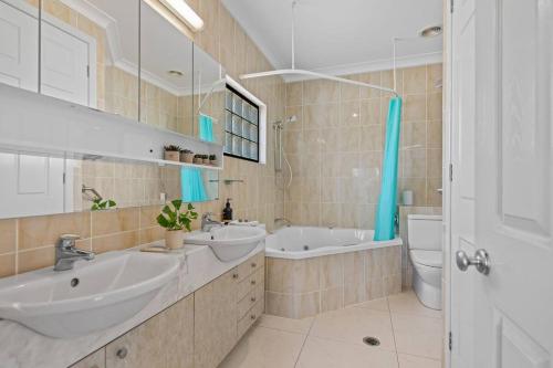 a bathroom with two sinks and a tub and a toilet at Lux Penthouse, Private Rooftop in Brisbane