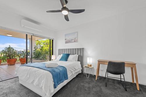 a bedroom with a bed with a ceiling fan and a desk at Lux Penthouse, Private Rooftop in Brisbane