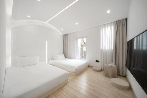 a white bedroom with two beds and a tv at 鼓浪屿吕舍民宿 in Gulang Yu