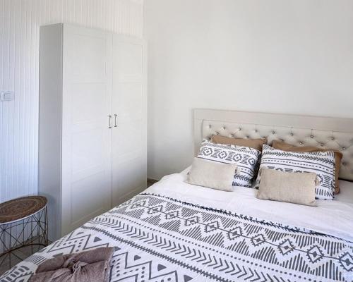 a white bedroom with a large bed with pillows at SeaSun in Ashqelon
