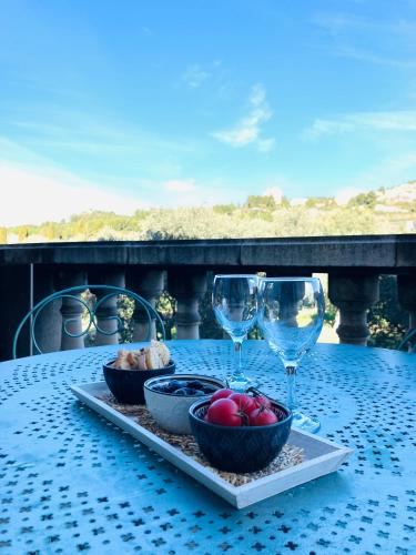 - une table avec deux verres à vin et une assiette de nourriture dans l'établissement Appartement vue magnifique sur les Alpilles, résidence avec Piscine, à Paradou