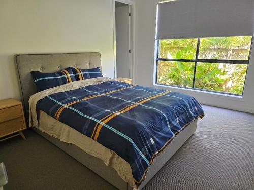 ein Schlafzimmer mit einem Bett mit blauer Bettdecke und einem Fenster in der Unterkunft Bayside Home in Highett