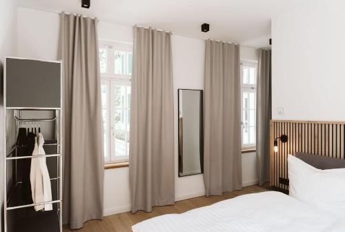 ギュータースローにあるVilla am Stadtpark - Boardinghouseのベッドと2つの窓がある寝室