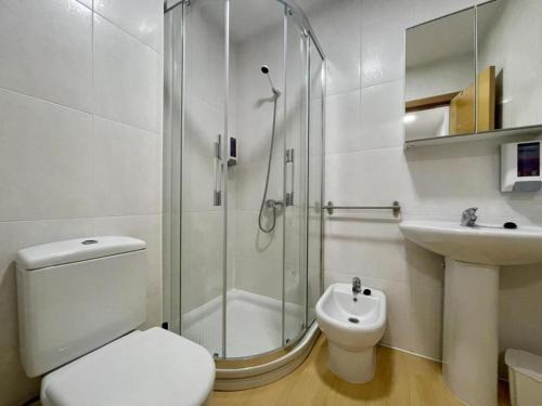 a bathroom with a shower and a toilet and a sink at Apartamento Playa de Quenxe in Corcubión