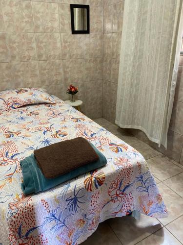 a bedroom with a bed with a comforter on it at Pousada da Vânia in Vespasiano