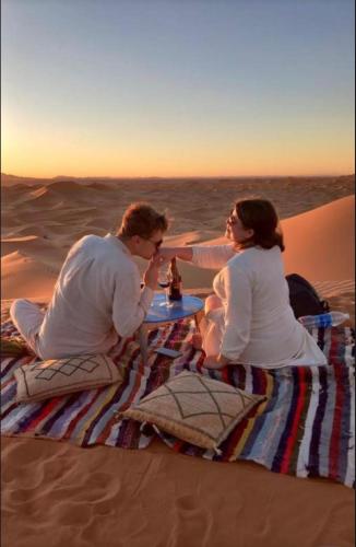 a man and woman sitting at a table in the desert at Merzouga Lovely Luxury Camp in Merzouga