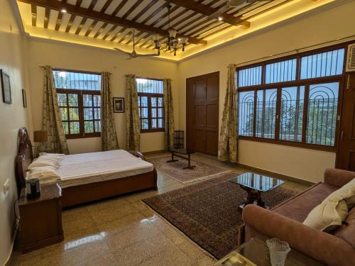a bedroom with a bed and a couch and windows at Mulberry Garden in Varanasi