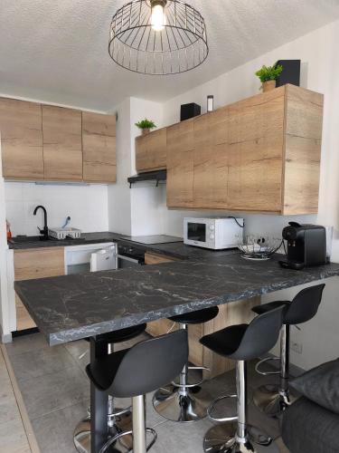 - une cuisine avec un comptoir en marbre et des tabourets de bar dans l'établissement Appartement la Foux d allos, à Allos
