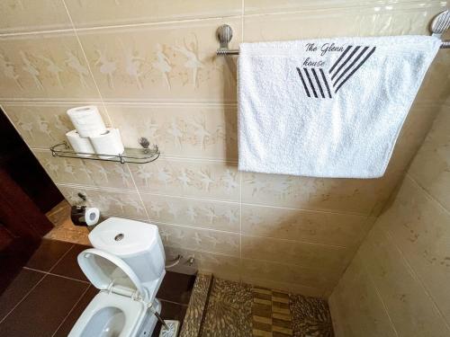 a bathroom with a toilet and a towel on the wall at The Glenn House in Apenkwa