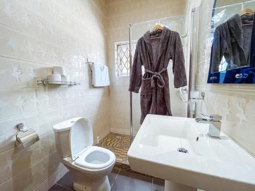a white bathroom with a toilet and a sink at The Glenn House in Apenkwa