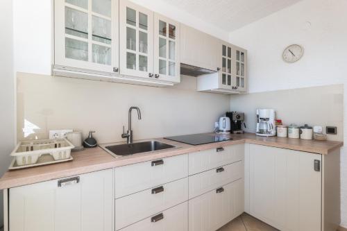 a kitchen with white cabinets and a sink at Villa Eugenia in Košljun