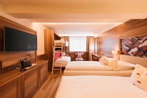 a hotel room with two beds and a flat screen tv at Arlberghaus in Zürs am Arlberg