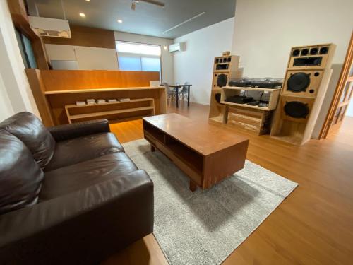 a living room with a leather couch and a coffee table at 民泊灯台もと暮らし-The Light House- in Saiki
