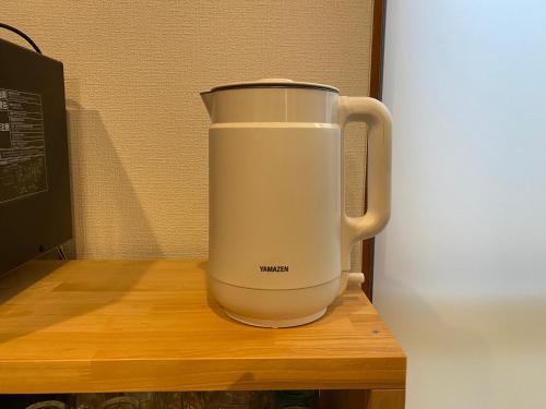 a white food processor sitting on a wooden table at 民泊灯台もと暮らし-The Light House- in Saiki
