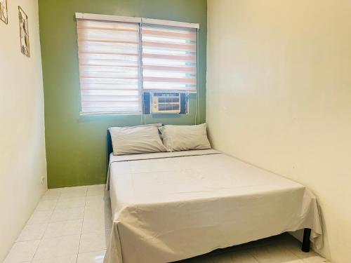 a small bed in a room with a window at The Alusiman Home - 4 bedroom home in Iloilo City