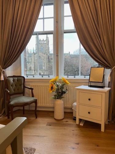 um quarto com uma janela com um vaso de flores e uma mesa com em Carvetii - Abbey View, 1st Floor Flat, City Centre em Dunfermline