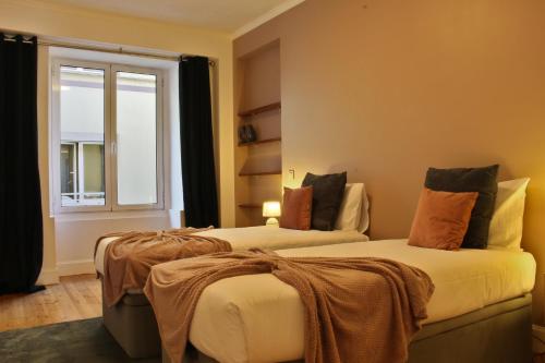 two beds in a room with a window at Like Home III - Apartamento com 2 quartos, ideal para famílias e amigos in Funchal