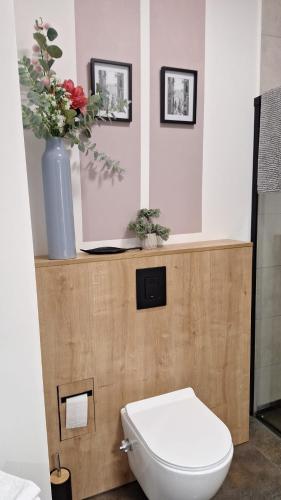 a bathroom with a toilet and a vase with flowers at La Casa in Piotrków Trybunalski