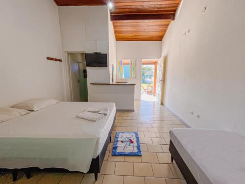 a white room with two beds and a kitchen at Pousada Riviera by Concavus in Caraguatatuba