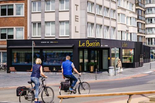two people riding bikes in front of a store at Hotel du Bassin in Ostend