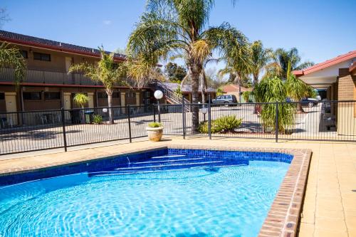 a swimming pool in front of a building with palm trees at Mildura Motor Inn in Mildura