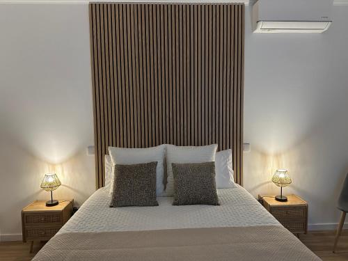 a bedroom with a white bed with two lamps at Achadinha Sunset House in Achadinha