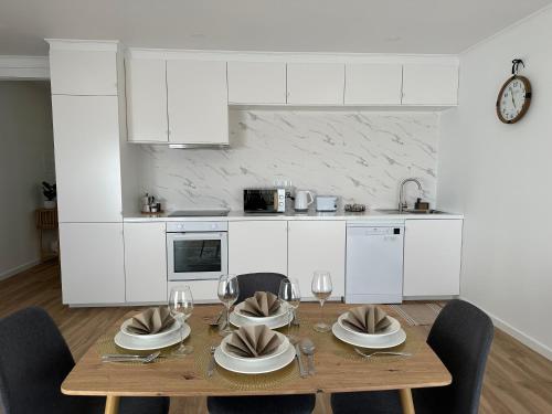 a kitchen with a wooden table with plates and wine glasses at Achadinha Sunset House in Achadinha